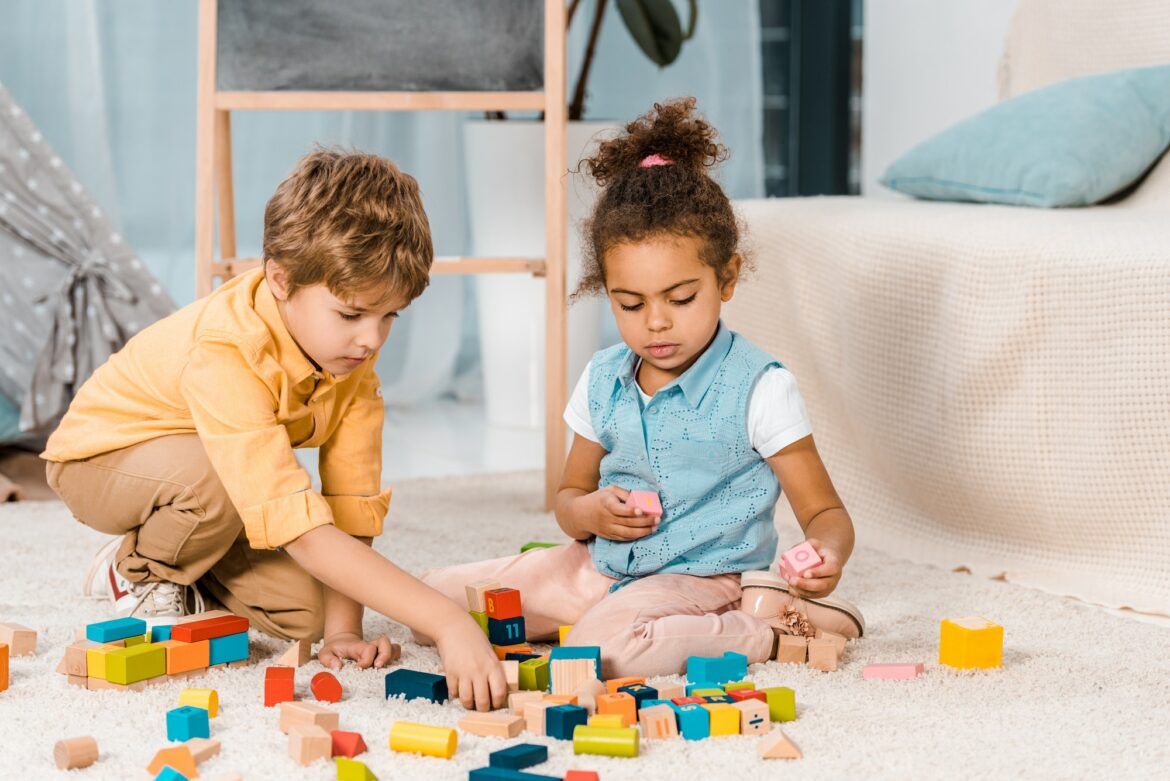 adorable-multiethnic-kids-playing-with-colorful-wooden-blocks-on-carpet.jpg