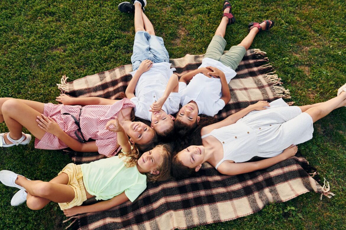 having-a-rest-and-laying-down-group-of-happy-kids-is-outdoors-on-the-sportive-field-at-daytime.jpg