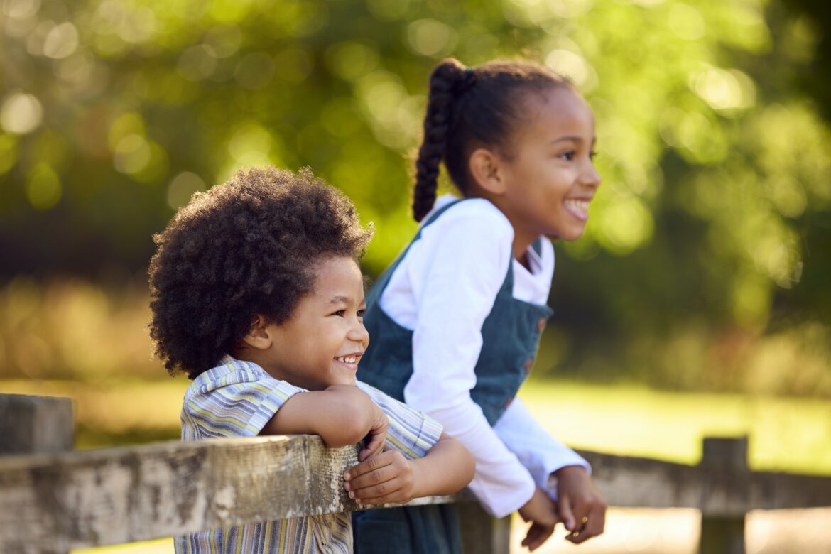 two-smiling-children-leaning-on-fence-on-walk-in-countryside.jpg